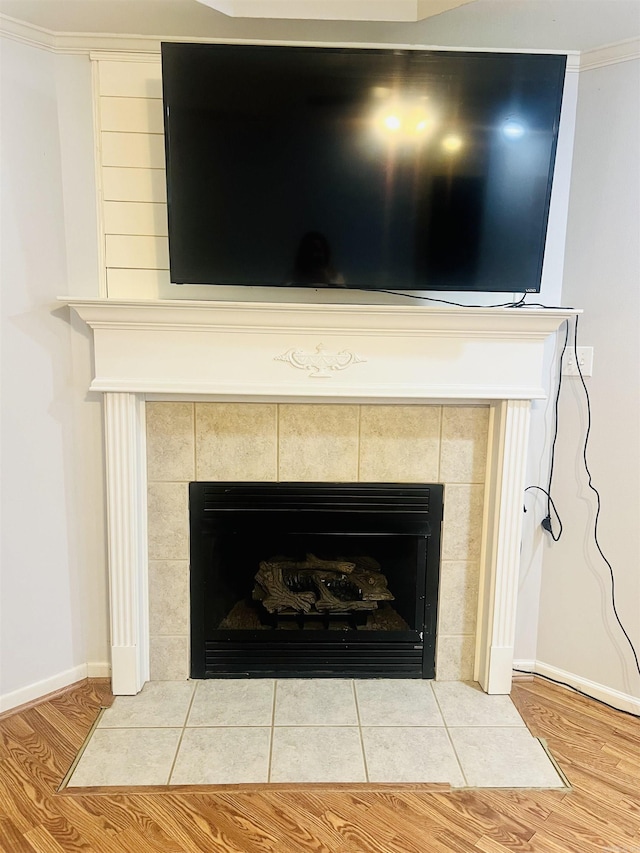 details with wood-type flooring, crown molding, and a tiled fireplace