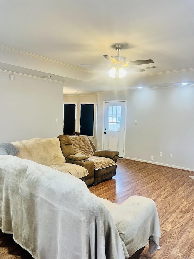 living room with hardwood / wood-style flooring, ceiling fan, and crown molding