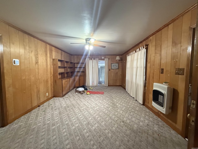 empty room with heating unit, wooden walls, ornamental molding, and carpet flooring