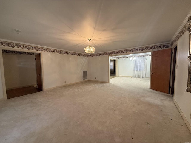 unfurnished room with ornamental molding, light colored carpet, visible vents, and a chandelier