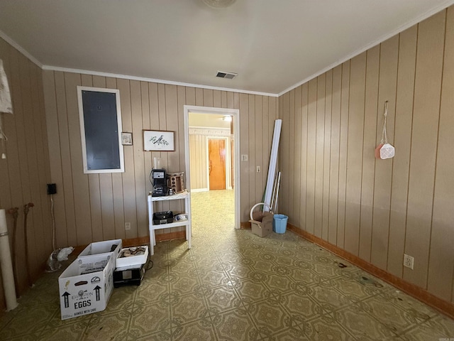 interior space with ornamental molding, wooden walls, visible vents, and baseboards