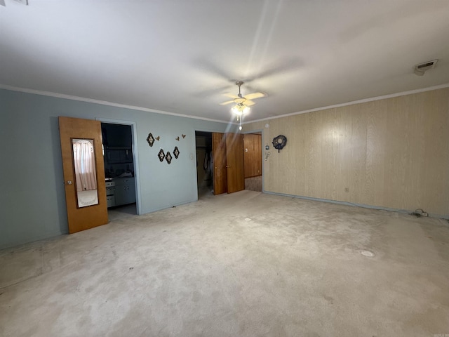 interior space featuring ornamental molding, ceiling fan, carpet floors, and visible vents