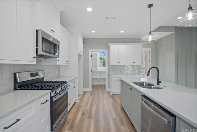 kitchen featuring pendant lighting, sink, white cabinetry, and stainless steel appliances