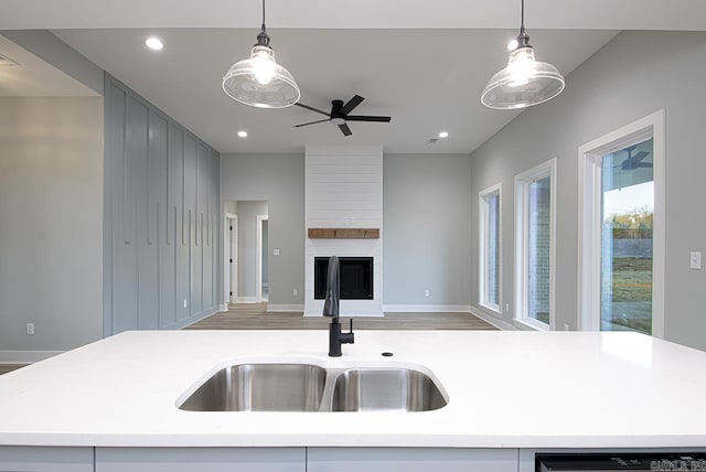 kitchen with decorative light fixtures, a center island with sink, and sink