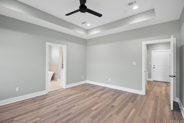 spare room featuring light hardwood / wood-style floors, ceiling fan, and a tray ceiling