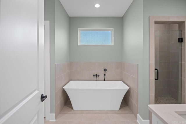 bathroom with tile patterned flooring, vanity, tile walls, and plus walk in shower