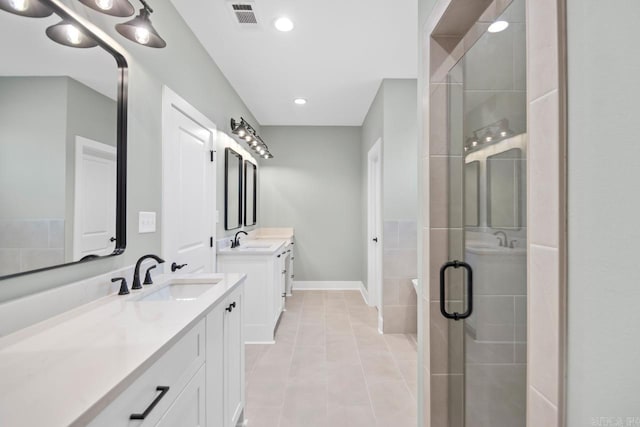 bathroom featuring tile patterned floors, a shower with door, and vanity