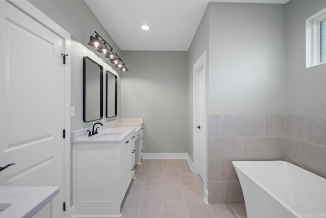 bathroom featuring tile patterned floors, a washtub, vanity, and tile walls