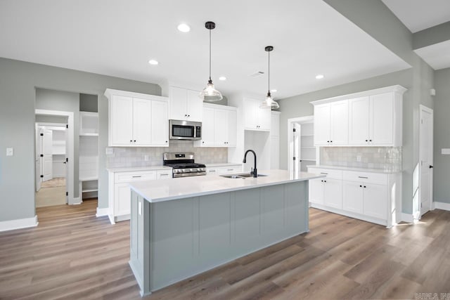 kitchen featuring white cabinets, sink, appliances with stainless steel finishes, and an island with sink