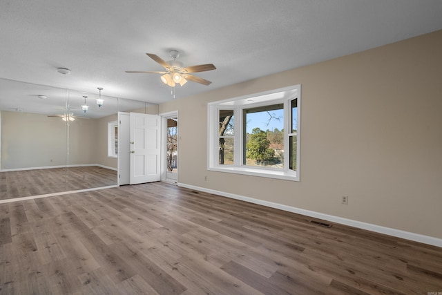 empty room with a textured ceiling, hardwood / wood-style flooring, and ceiling fan