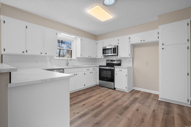 kitchen with decorative backsplash, white cabinets, and appliances with stainless steel finishes