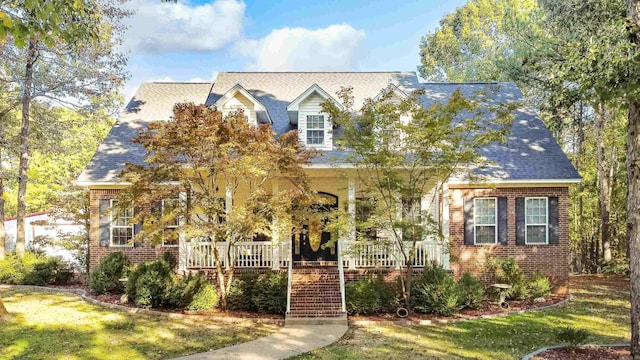 cape cod home with covered porch and a front yard