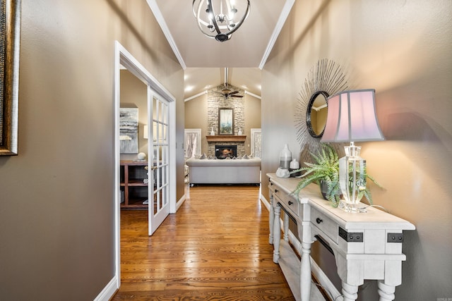 hall featuring a chandelier, light hardwood / wood-style floors, lofted ceiling, and ornamental molding