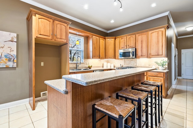 kitchen with sink, a center island, crown molding, a breakfast bar, and light tile patterned floors