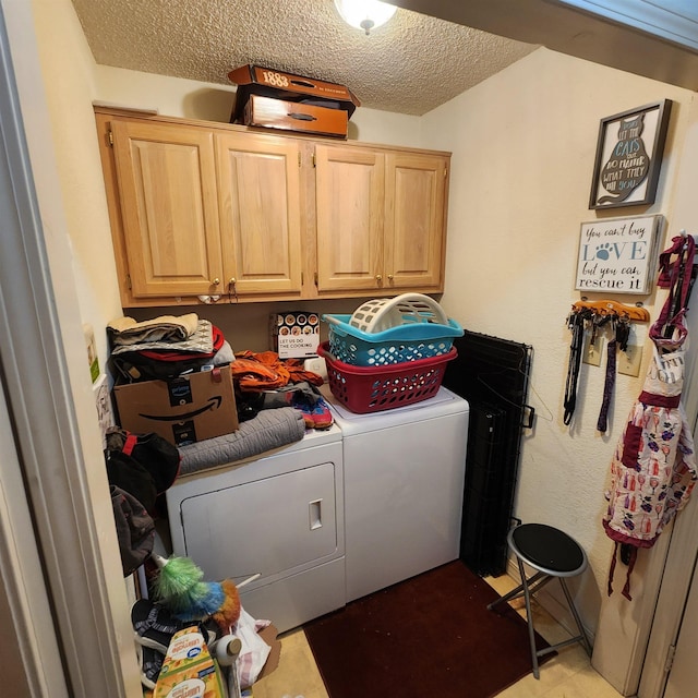 laundry room featuring washer and clothes dryer, cabinets, and a textured ceiling