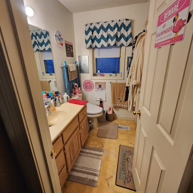 bathroom featuring vanity, a textured ceiling, and toilet