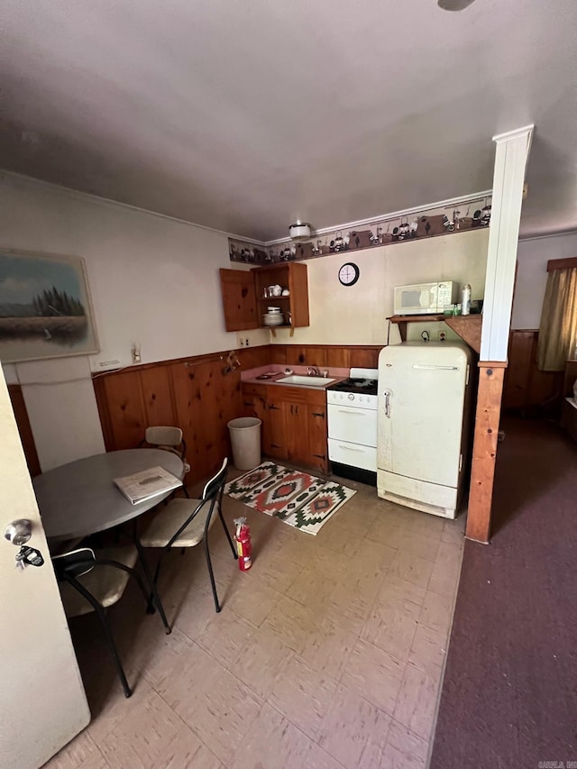 kitchen featuring washer / dryer, white appliances, wooden walls, and sink