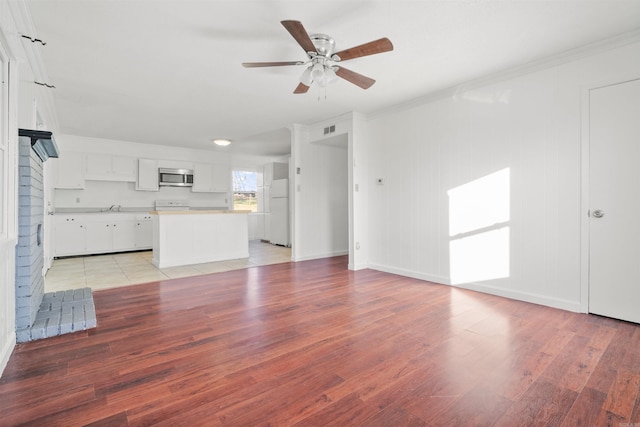 unfurnished living room featuring ceiling fan, sink, a brick fireplace, light hardwood / wood-style floors, and ornamental molding