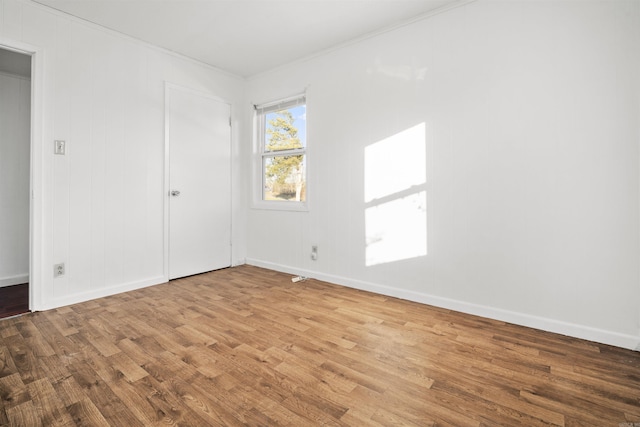 empty room with wood-type flooring and crown molding