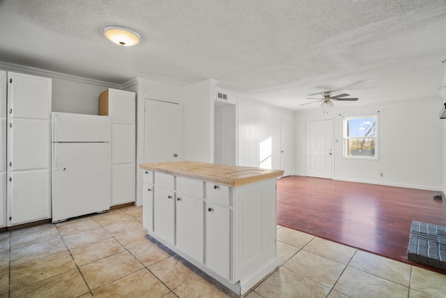 kitchen featuring ceiling fan, light tile patterned floors, white fridge, a textured ceiling, and white cabinets