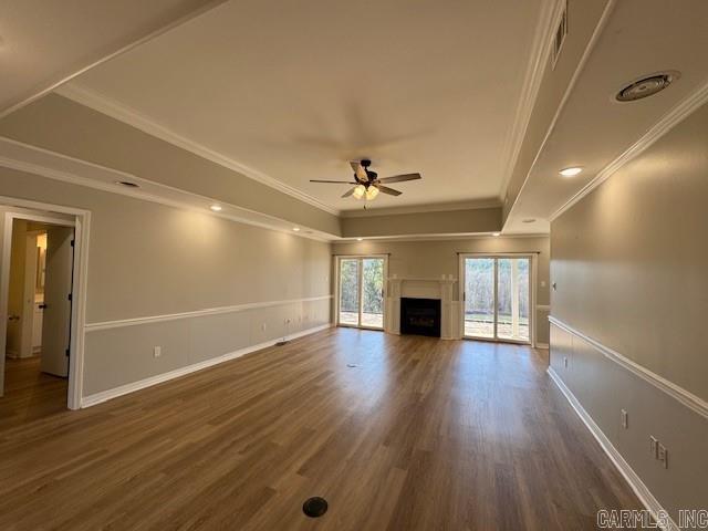 unfurnished living room featuring ceiling fan, dark hardwood / wood-style flooring, crown molding, and a tray ceiling