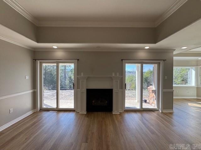 unfurnished living room with a raised ceiling, wood-type flooring, and ornamental molding