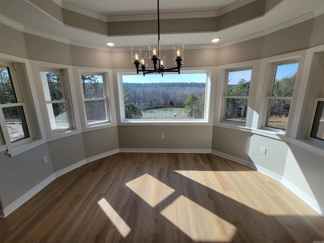 unfurnished dining area featuring a raised ceiling, ornamental molding, and a chandelier