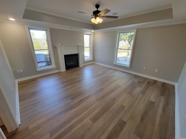 unfurnished living room with hardwood / wood-style floors, ceiling fan, a raised ceiling, and crown molding