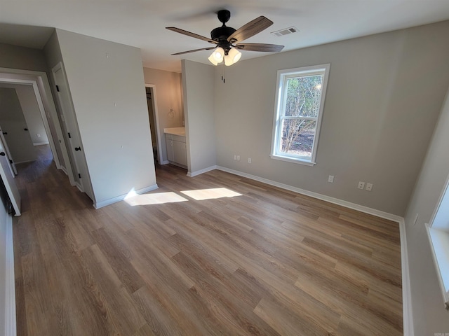 interior space with ceiling fan, light wood-type flooring, and connected bathroom