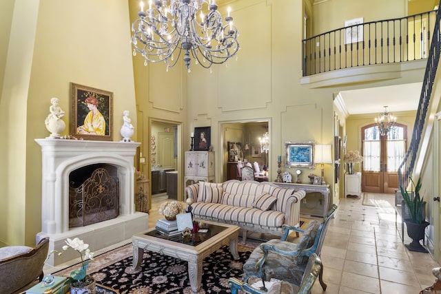 living room with french doors, a towering ceiling, ornamental molding, an inviting chandelier, and light tile patterned flooring