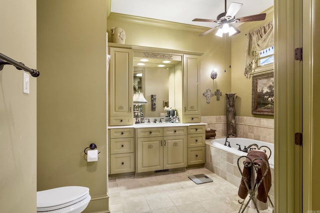 bathroom with ornamental molding, vanity, ceiling fan, a relaxing tiled tub, and toilet