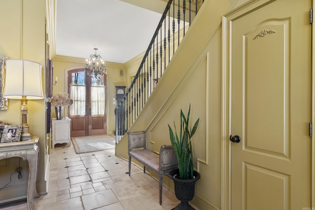 entrance foyer featuring french doors, ornamental molding, and a notable chandelier