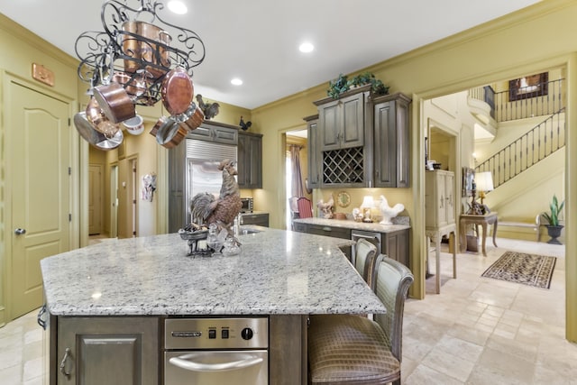 kitchen featuring a kitchen bar, crown molding, a kitchen island, light stone counters, and dark brown cabinetry