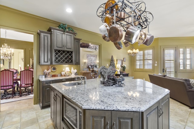 kitchen with a center island with sink, stainless steel microwave, ornamental molding, and sink