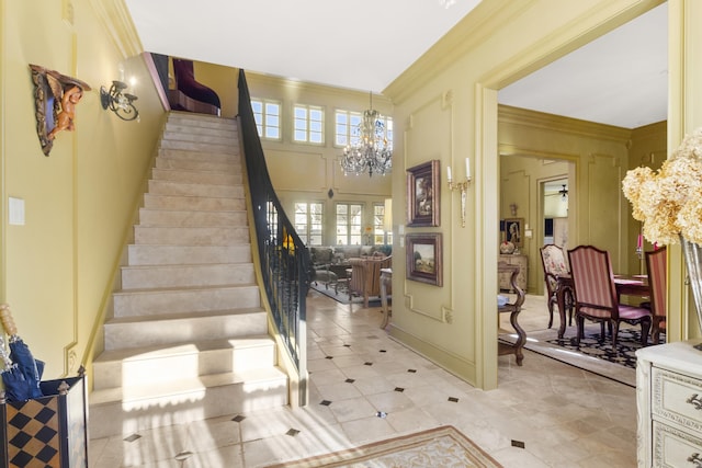 entryway with a towering ceiling, ornamental molding, and an inviting chandelier