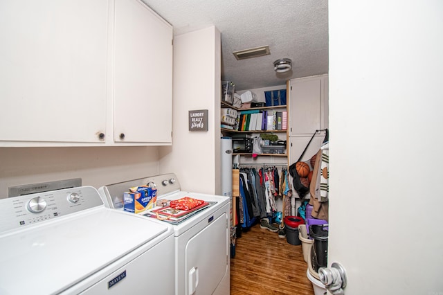 laundry room with cabinets, a textured ceiling, separate washer and dryer, and light hardwood / wood-style flooring