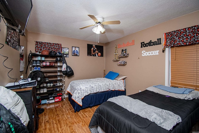 bedroom featuring ceiling fan, hardwood / wood-style floors, and a textured ceiling