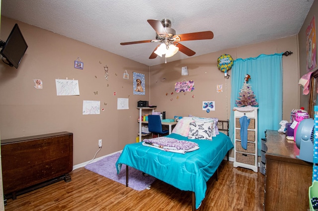 bedroom with ceiling fan, wood-type flooring, and a textured ceiling