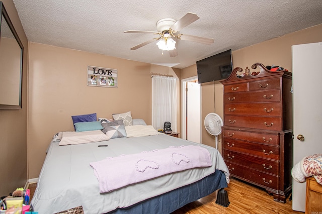 bedroom with ceiling fan, a textured ceiling, and light wood-type flooring