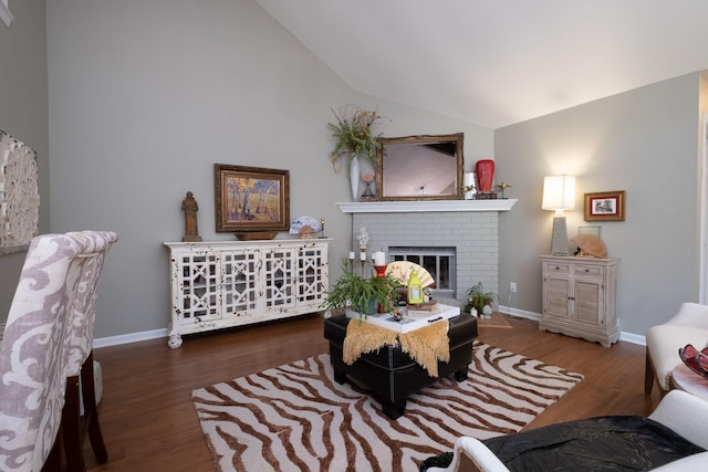 living room with dark hardwood / wood-style floors, vaulted ceiling, and a brick fireplace