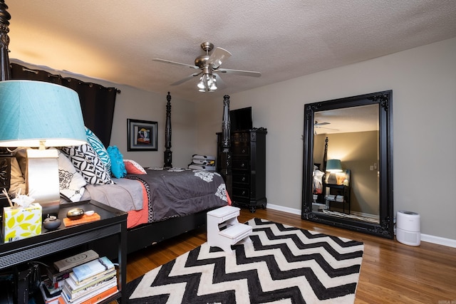 bedroom with a textured ceiling, ceiling fan, and dark wood-type flooring