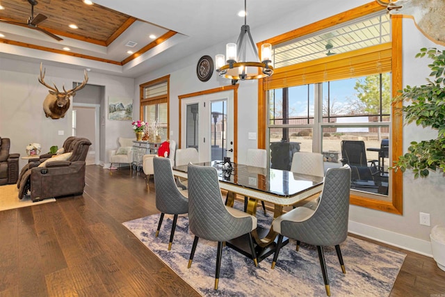 dining space featuring ceiling fan with notable chandelier, dark hardwood / wood-style floors, a raised ceiling, and wood ceiling