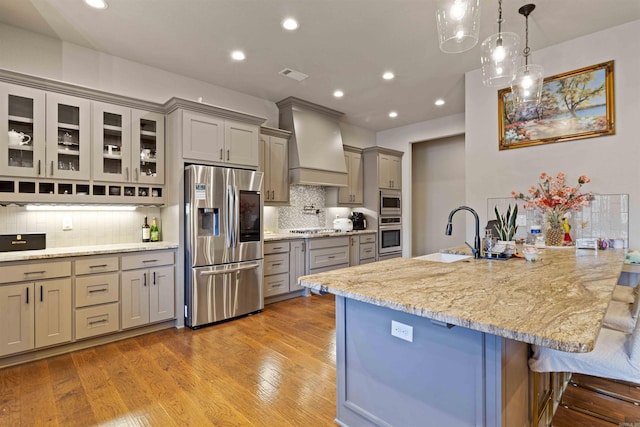 kitchen featuring sink, stainless steel appliances, tasteful backsplash, a kitchen breakfast bar, and premium range hood