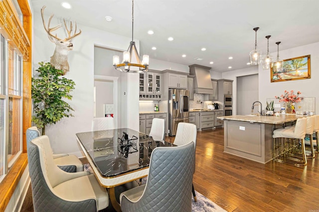 dining area featuring a chandelier, sink, and dark wood-type flooring