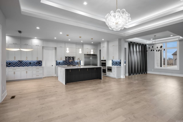 kitchen featuring pendant lighting, stainless steel appliances, and a raised ceiling