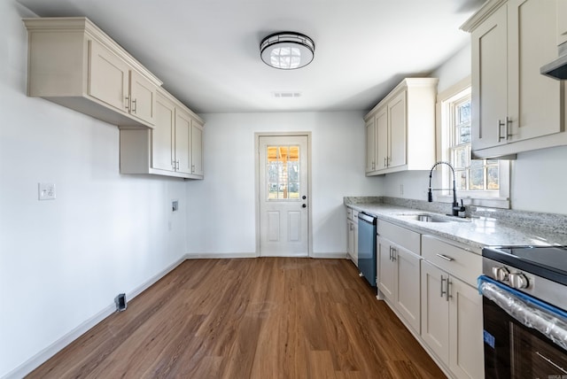 kitchen with appliances with stainless steel finishes, dark hardwood / wood-style floors, light stone counters, and sink