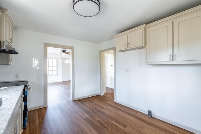 kitchen featuring light stone countertops, ceiling fan, wood-type flooring, and cream cabinetry