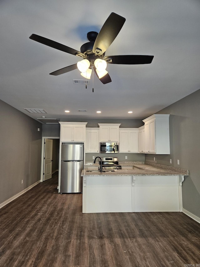 kitchen with kitchen peninsula, ceiling fan, appliances with stainless steel finishes, light stone counters, and white cabinetry