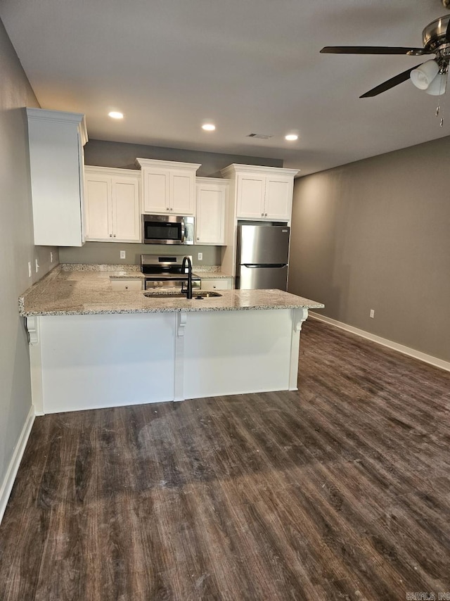 kitchen with white cabinets, sink, light stone counters, kitchen peninsula, and stainless steel appliances