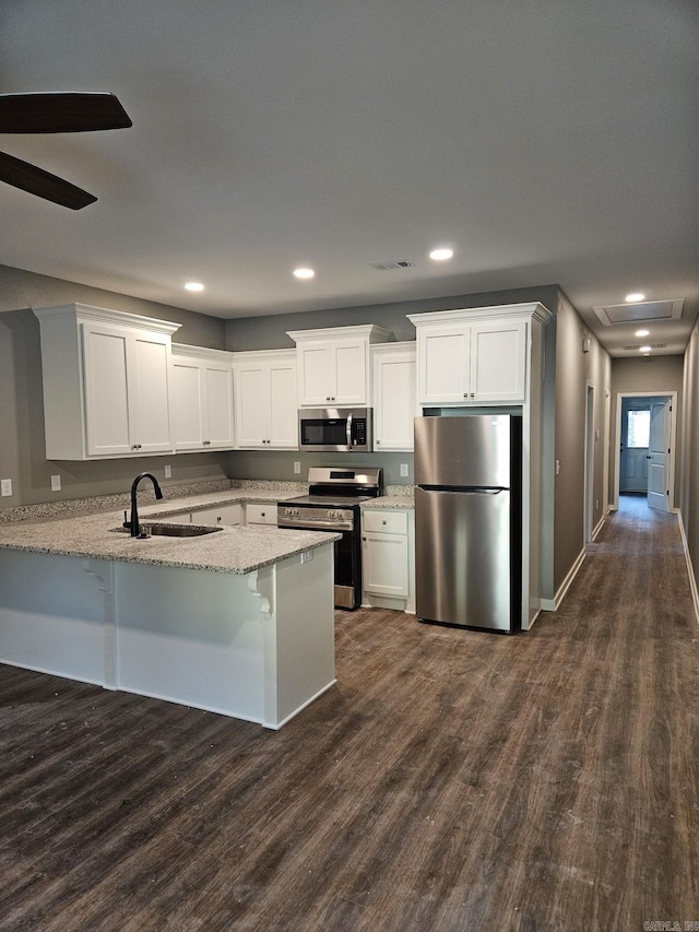 kitchen featuring kitchen peninsula, appliances with stainless steel finishes, white cabinetry, and sink